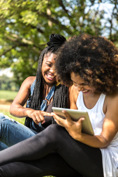 istock Afro friends using digital tablet in the park 817409580