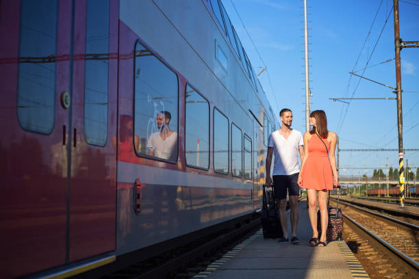 istock Happy young caucasian couple walking next to the train, pulling suitcases, wearing casual summer clothes 817410020