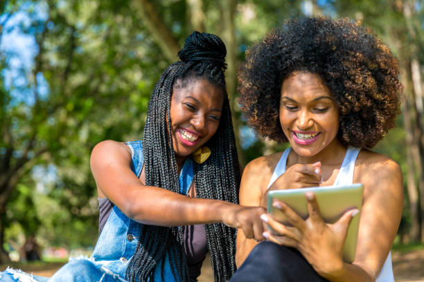istock Afro friends using digital tablet in the park 817414704