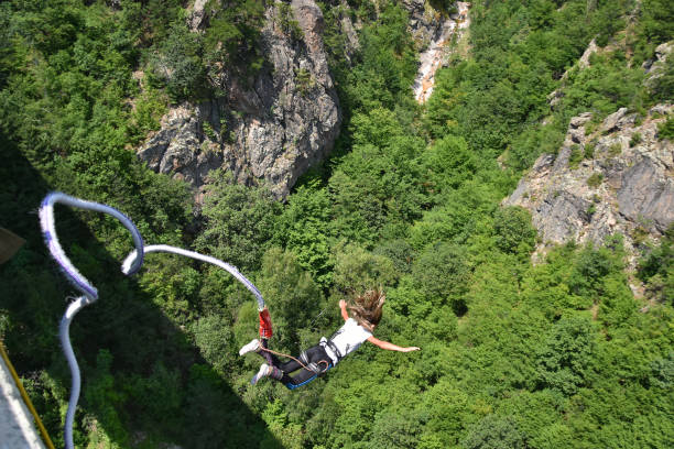 Bungee jumping Klisura, Bulgaria - July 15, 2017: Bungee jumper girl with winded hair falling down from a 230-feet high bridge, rocks and green trees seen at the background bungee jumping stock pictures, royalty-free photos & images