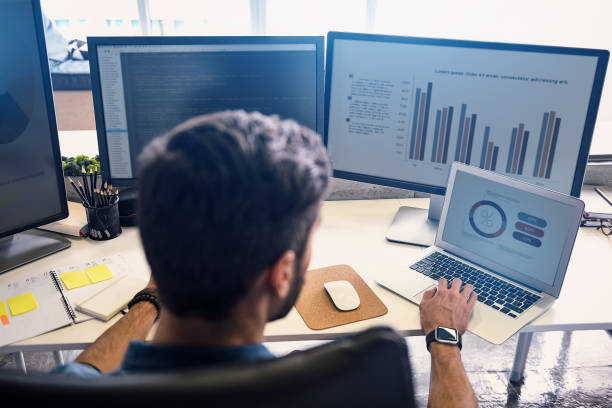 Male doing estimation on screen Man creating statistics in modern office. He working on digital devices while sitting at table and turning back to camera big data stock pictures, royalty-free photos & images