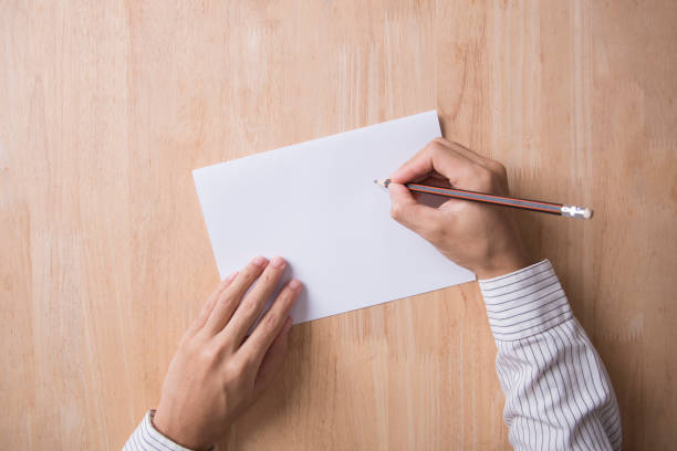 istock business hand writing note paper on wood table office.Top View with copy space for input the text. 817452578