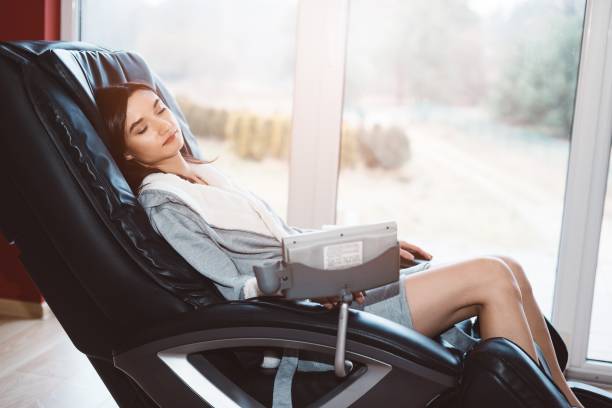 Young woman relaxing on the massaging chair stock photo