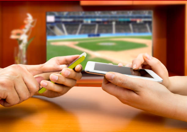 betting in baseball Friends using mobile phone and betting during a baseball match bet on cricket online stock pictures, royalty-free photos & images