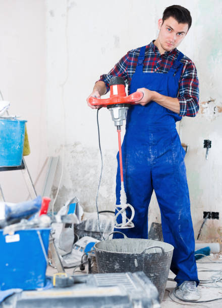 istock Builder mixing plaster in bucket with electric mixer 817469326