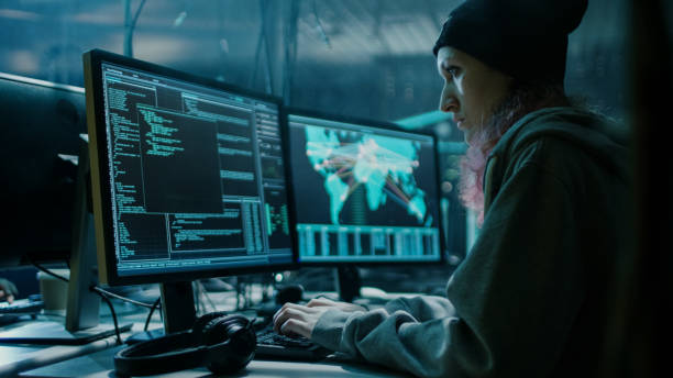 istock Nonconformist Teenage Hacker Girl Using her Computer to Organize Malware Attack on Global Scale. She's in Underground Secret Location Surrounded by Displays and Cables. 817486126