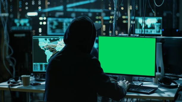 istock Teenage Hacker is Working With his Computer with Green Screen Mock-up Display Infect Servers and Infrastructure with Malware. His Hideout is Dark, Neon Lit and Has Multiple displays. Template Green Screen. 817486128