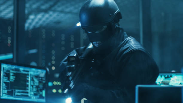istock Cyber War Special Forces Fully Armed Soldier Uncovers Internationally Wanted Hacker's Hideout Place. Lair is Full of Monitors, Cables and Has Neon Lights. 817486208