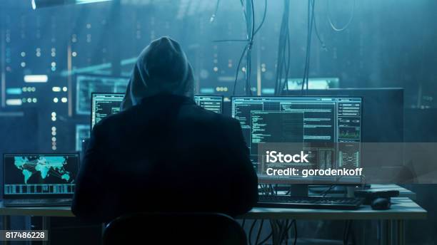 Dangerous Hooded Hacker Breaks Into Government Data Servers And Infects Their System With A Virus His Hideout Place Has Dark Atmosphere Multiple Displays Cables Everywhere Stock Photo - Download Image Now