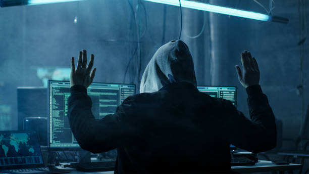 istock Hacker with Rised Handed. He is being arrested. Hideout is Dark and Full of Computer Equipment. 817486398