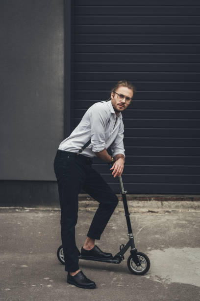 istock Handsome stylish young man in spectacles posing with scooter and looking at camera 817493898