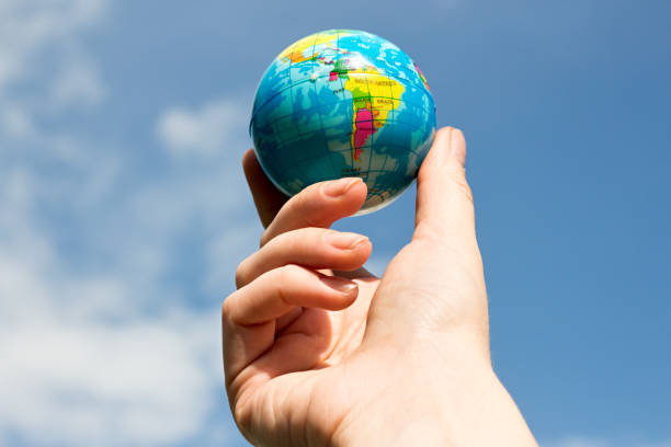 istock woman's hand with globe on blue sky background 817502366