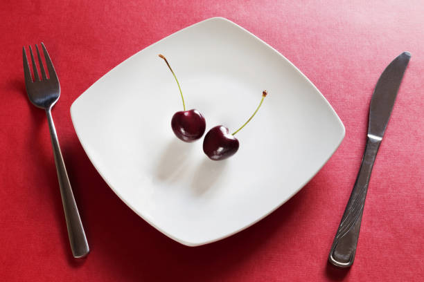 Diet white plate with cherry, fork and knife