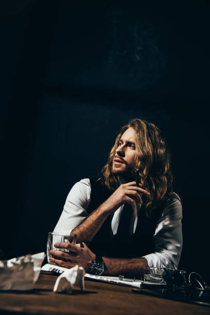 istock Handsome stylish young man drinking alcohol and smoking cigar while sitting at table 817513796
