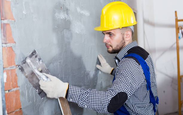 istock Smiling craftsperson in the helmet is plastering the wall 817525174