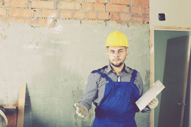 istock Male in the helmet ready is plastering the wall 817525758