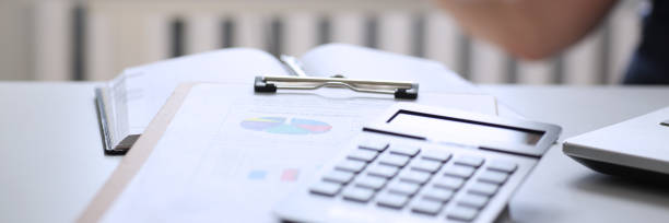 Black calculator and financial statistics on clipboard pad