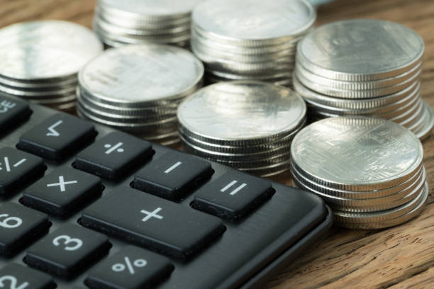 enfoque selectivo en calculadora con pila de monedas en el fondo en tabla de madera como financieros ahorro concepto - magnification coin equipment european union currency fotografías e imágenes de stock