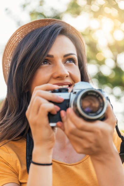 istock Smiling young woman using a camera to take photo. 817544504