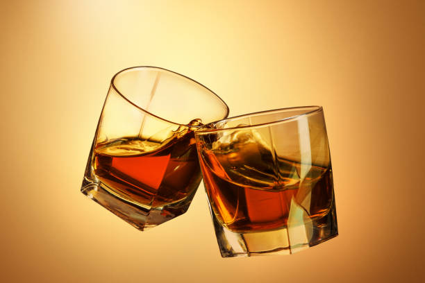 istock Two whiskey glasses clinking together on brown 817548252