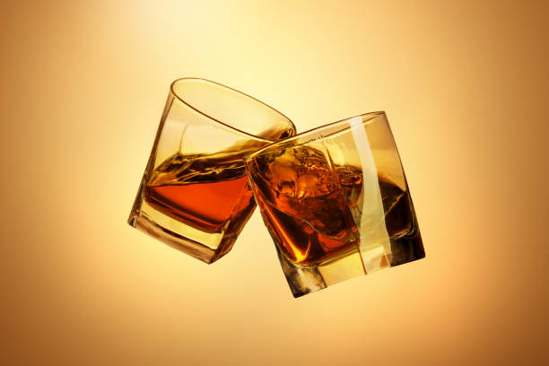 istock Two whiskey glasses clinking together on brown 817548418