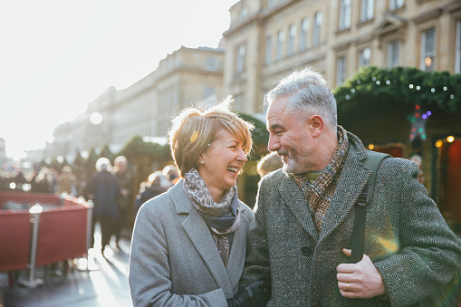A mature married couple are walking through a Christmas market together.