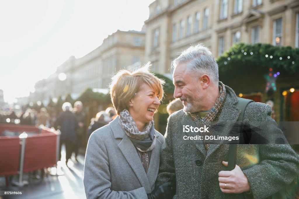 Mature Couple In Christmas Market A mature married couple are walking through a Christmas market together. Christmas Stock Photo