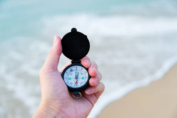 człowiek ręka trzyma kompas na plaży - compass exploration the way forward beach zdjęcia i obrazy z banku zdjęć