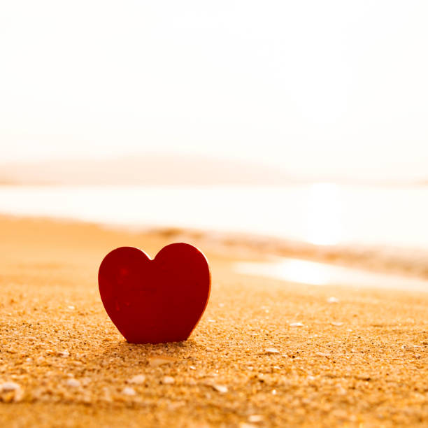 istock Red heart shape on the golden beach 817575458