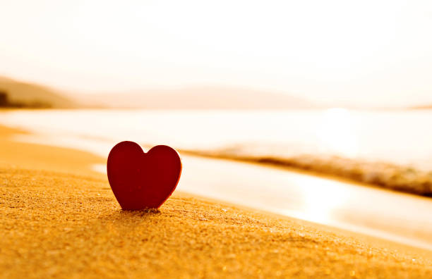 istock Red heart shape on the golden beach 817583750