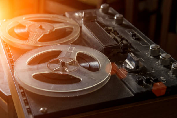Close-up of recorder with reel-to-reel tape in recording studio.