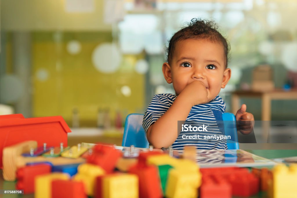 Happy baby playing with toy blocks. Happy baby playing with toy blocks in the kindergarten. Baby - Human Age Stock Photo