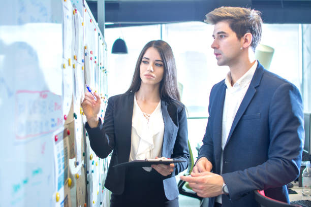 istock Business people talking and pointing something on a white board in the office. 817601350