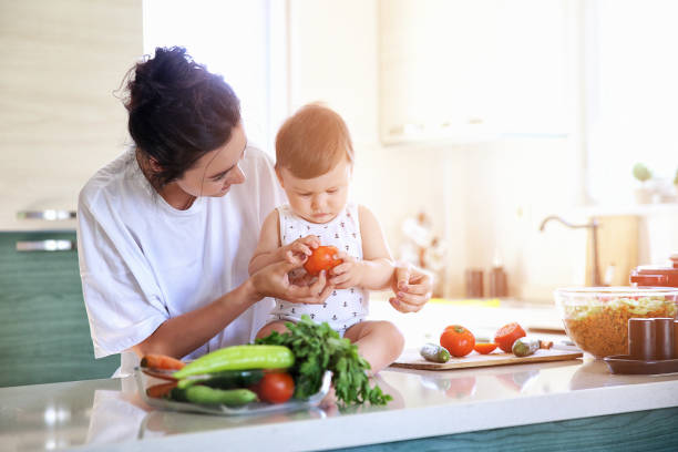 Mother of a woman with a baby cooks the food stock photo