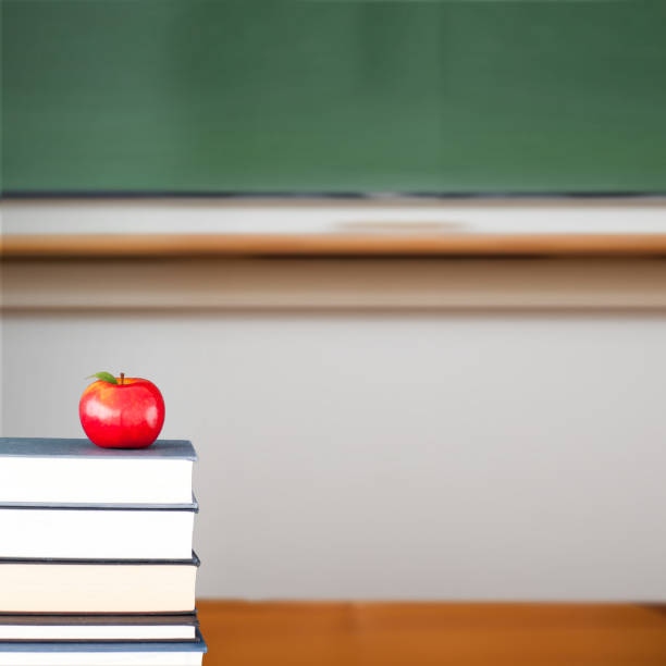 istock Red apple on pile of books in classroom 817620654
