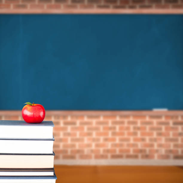 istock Red apple on pile of books in classroom 817621024