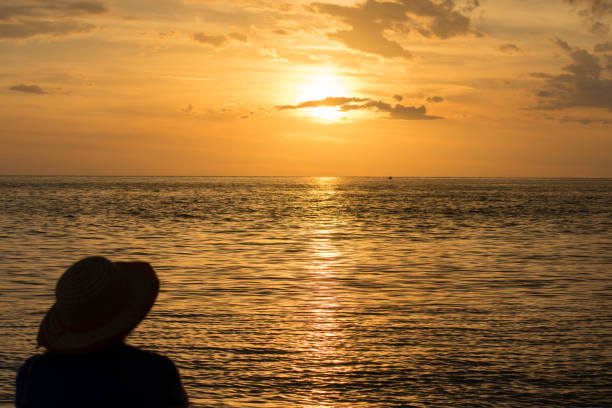 istock Woman on beach against golden sunset 817648530
