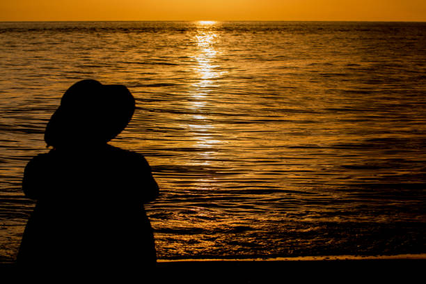 istock Woman on beach against golden sunset 817649548
