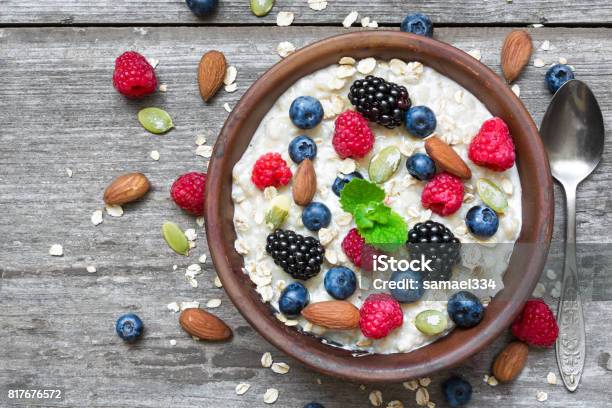 Photo libre de droit de Bouillie De Flocons Davoine Aux Fruits Et Noix Dans Un Bol Avec Une Cuillère Pour Petit Déjeuner Sain Sur Fond En Bois Rustique banque d'images et plus d'images libres de droit de Baie - Partie d'une plante