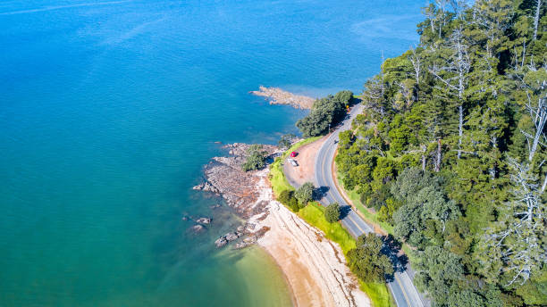 vista aérea em uma estrada que corre ao longo da costa do mar. auckland, nova zelândia. - pacific coast highway - fotografias e filmes do acervo