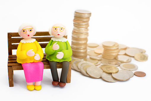 Doll, grandma sitting on a chair next to a pile of money, concept Having money for life is not difficult.