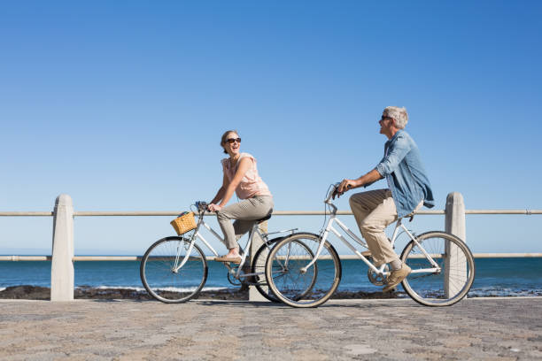 gelukkige casual paar gaan voor een fiets rijden op de pier - rijden activiteit stockfoto's en -beelden