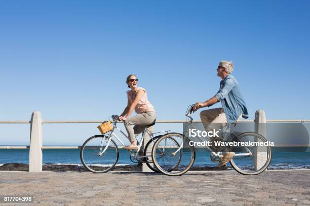 Happy Casual Couple Going For A Bike Ride On The Pier Stock Photo - Download Image Now