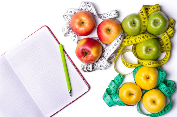 istock Healthy Eating: Fresh apples, measuring tape and notepad on white table. 817712738