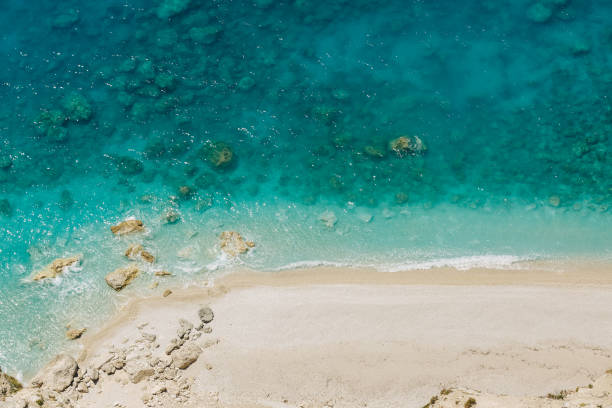 istock Aerial view to pristine beach with rocky bay and waves crashing 817754550