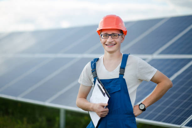 istock Worker in helmet standing, solar panels behind him. 817807084