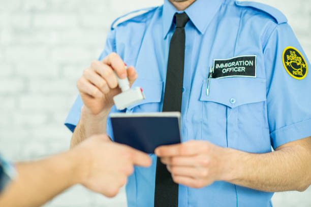 Stamping a Passport An unrecognizable immigration officer is in uniform. In this frame, he is stamping a passport allowing an unrecognizable person who is immigrating to enter into a new country. customs agent stock pictures, royalty-free photos & images