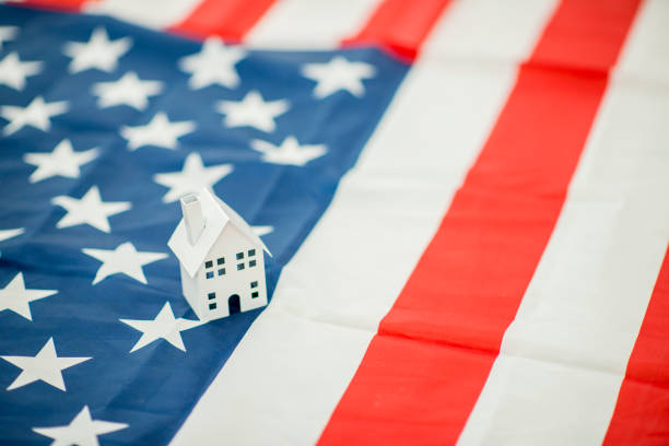 In this frame a small toy house sits on an American flag to represent immigration and making a home in a new country.