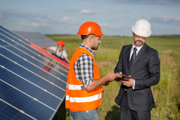 istock Businessman signing contract with foreman, technician examining solar panels at backdrop. 817831532