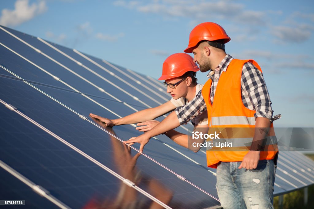 Worker and foreman maintaining solar energy panel. Worker and foreman maintaining solar energy panel. Technicians checking equipment for solar energy station. Solar Panel Stock Photo